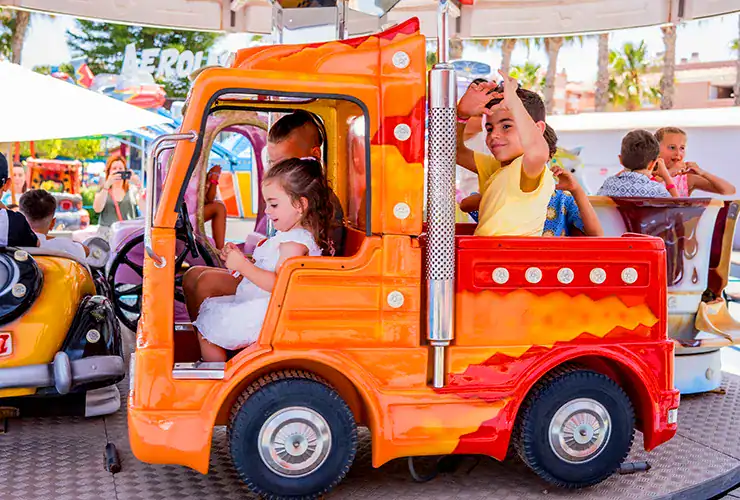 Niños montando en el carrusel infantil de Pola Park, parque de atracciones de Santa Pola